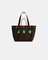 The Painted Perfect Weekday Tote is a brown cotton bag with dark handles and the green initials “JMW” embroidered on the front. This personalized tote features a structured silhouette and silver snap accents near the top edge.