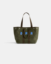 The Perfect Weekday Tote is a green suede bag with brown handles, featuring large blue and white 