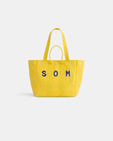 The Perfect Weekday Tote is a bright yellow cotton bag with two handles and bold blue 