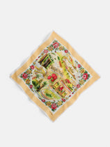 The Travel Scarf in Cotton Voile features a yellow border, vibrant illustrations of California landmarks, palm trees, red flowers, and "California" in script at the center, inspired by vintage bandanas.