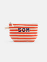 The Painted Perfect Striped Canvas Pouch features horizontal red and beige stripes, bold navy "SOM" lettering on the front, a left-side beige strap, and a secure zippered closure.