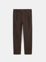 The Standard Pleated Pant in Chino is a pair of brown straight-leg pants featuring front pleats, a button and zip closure, side and back pockets, and crafted from soft cotton twill, shown laid flat on a white background.