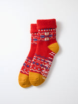A pair of RoToTo Snowflake Room Socks, made in Japan, featuring red, yellow, blue, and white geometric patterns with a fuzzy cuff and "ROTOTO" printed on the side, displayed on a white background.